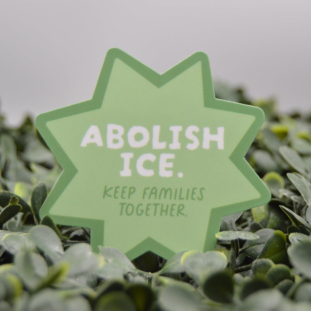 A light green star-shaped sign with the text 'ABOLISH ICE. KEEP FAMILIES TOGETHER.