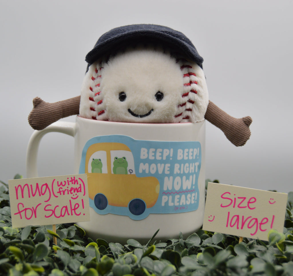 A plush baseball character wearing a dark navy cap pops out of a white ceramic mug. The mug has a blue and yellow cartoon graphic and the text 'BEEP! BEEP! MOVE RIGHT NOW! PLEASE!'.